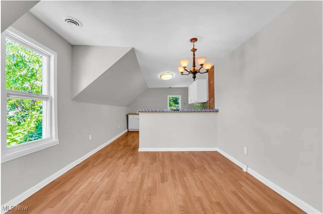 Additional living space featuring light wood-style flooring, healthy amount of natural light, and a chandelier