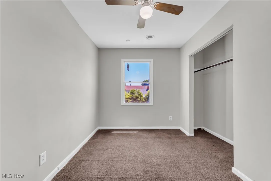 Unfurnished bedroom with carpet, a closet, and a ceiling fan