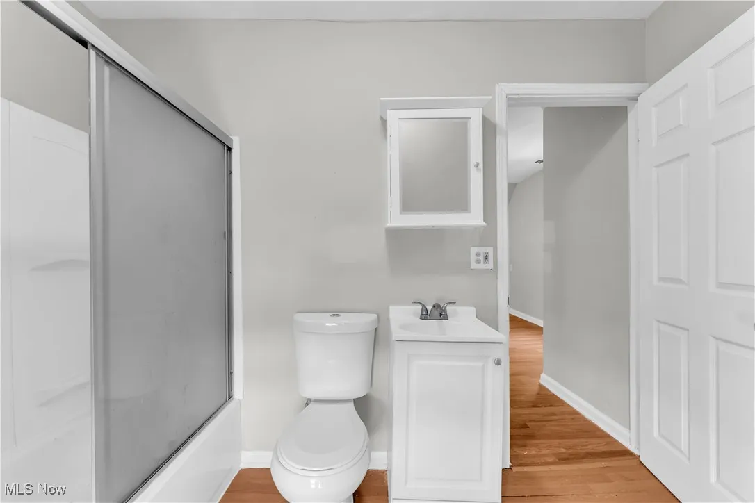 Full bathroom with vanity, wood finished floors, and combined bath / shower with glass door