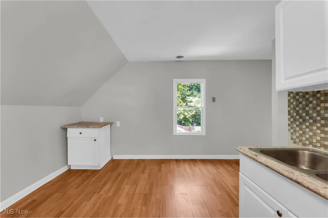 Bonus room with light wood-style flooring and vaulted ceiling