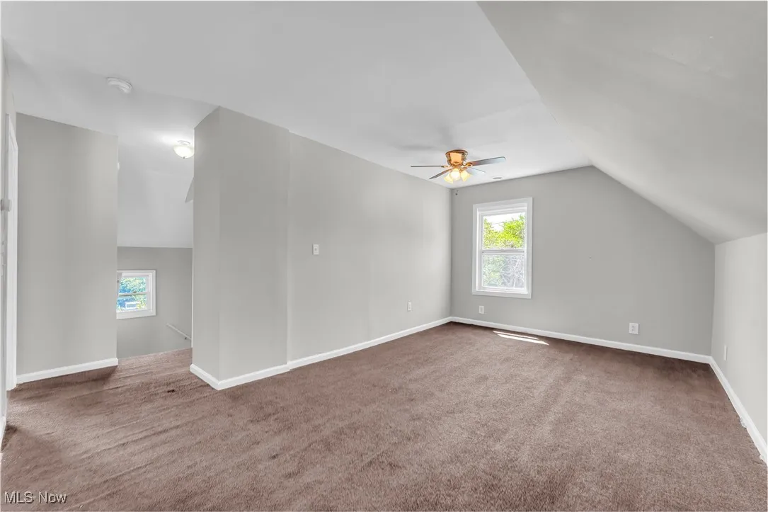 Additional living space with lofted ceiling, carpet flooring, and a ceiling fan