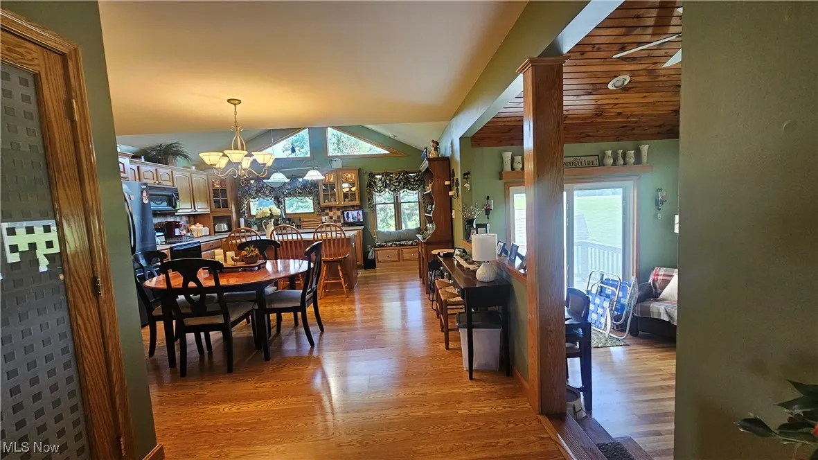 Dining room featuring light wood finished floors, lofted ceiling, a chandelier, and plenty of natural light