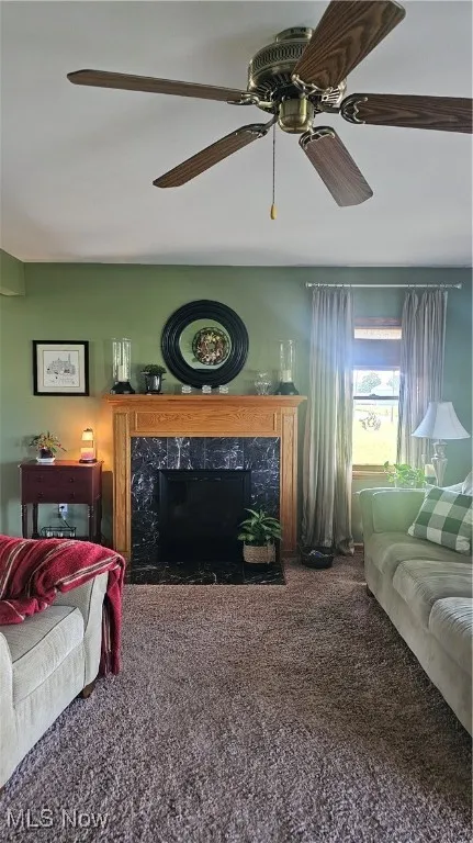 Living room featuring carpet flooring, a premium fireplace, and ceiling fan