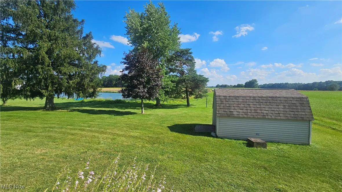View of green lawn featuring a storage unit and a water view