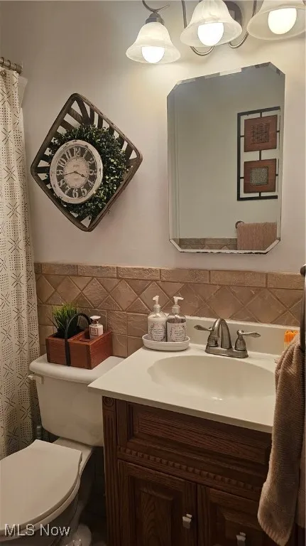 Bathroom with tile walls, vanity, and a wainscoted wall