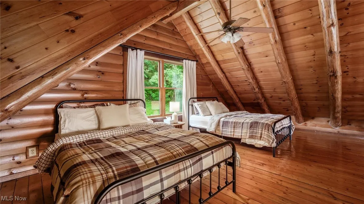 Bedroom with wooden ceiling, hardwood / wood-style flooring, and log walls