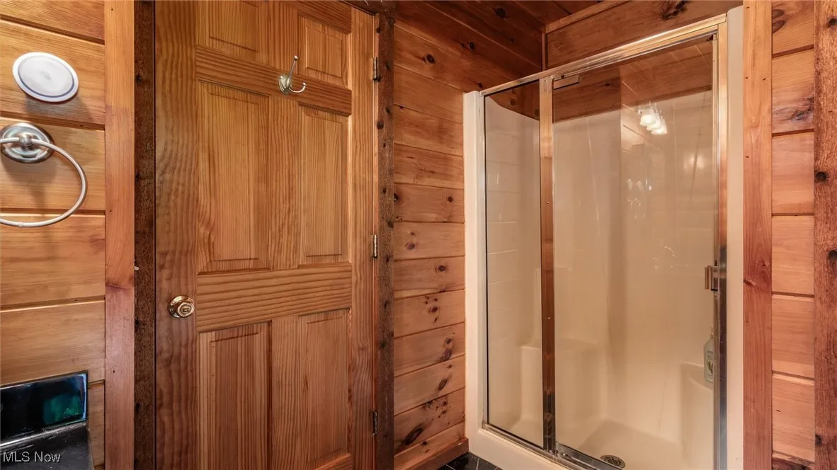 Full bath with a stall shower and wooden walls