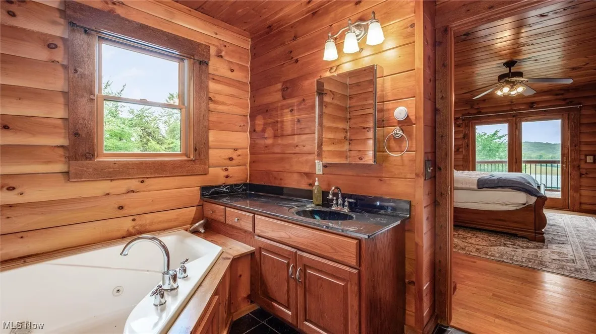 Bathroom featuring healthy amount of natural light, vanity, ensuite bath, a whirlpool tub, and wood ceiling