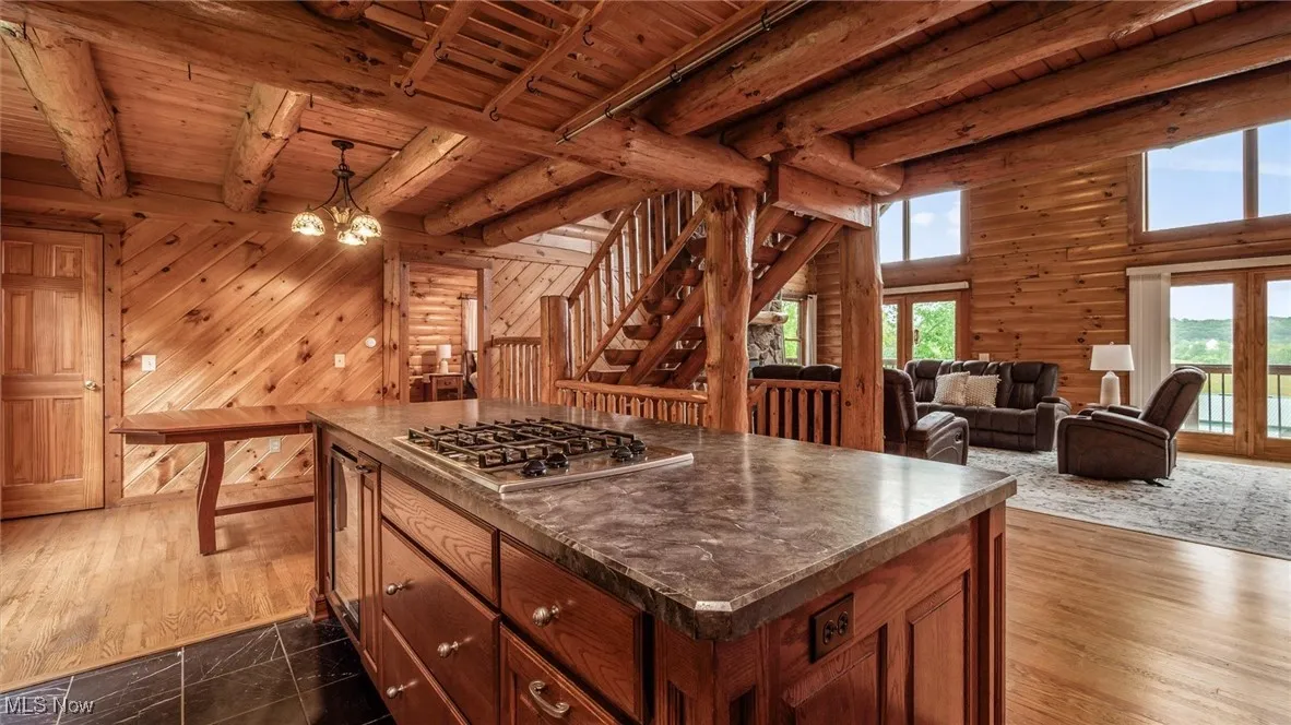 Kitchen with a chandelier, plenty of natural light, brown cabinets, wood walls, and a wooden ceiling with exposed beams