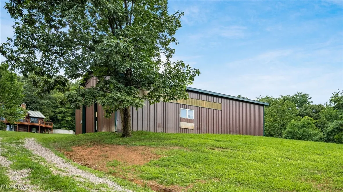View of side of home featuring a pole building, a lawn, an outbuilding, and driveway