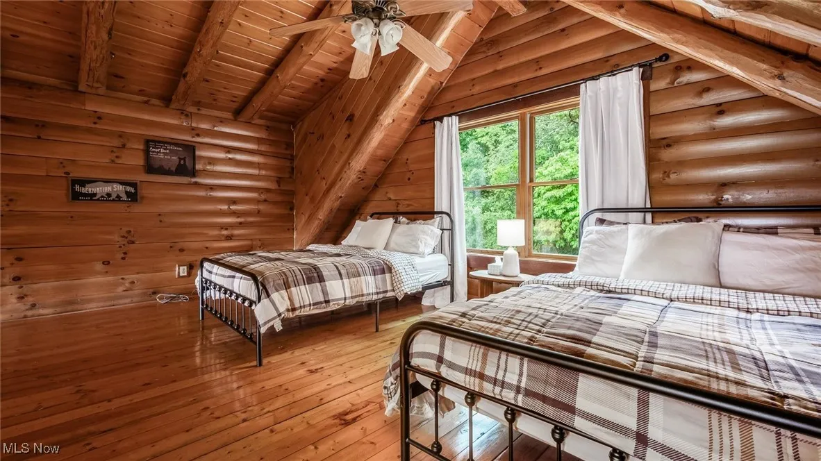 Bedroom featuring log walls, light wood-style flooring, and wooden ceiling