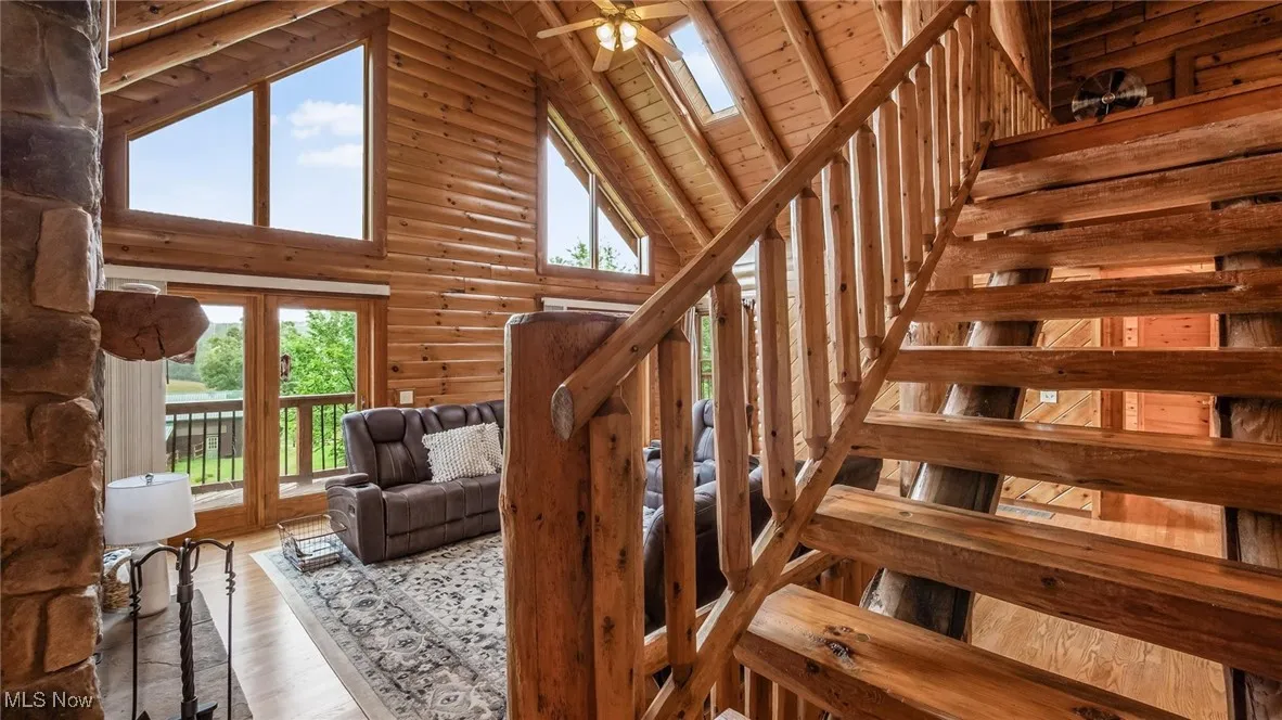 Stairway with healthy amount of natural light, high vaulted ceiling, wood finished floors, wooden ceiling, and ceiling fan