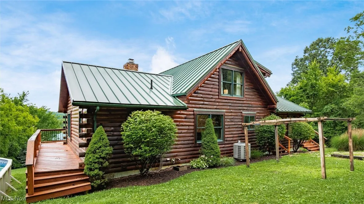 Back of house featuring a standing seam roof, log siding, a metal roof, and a chimney