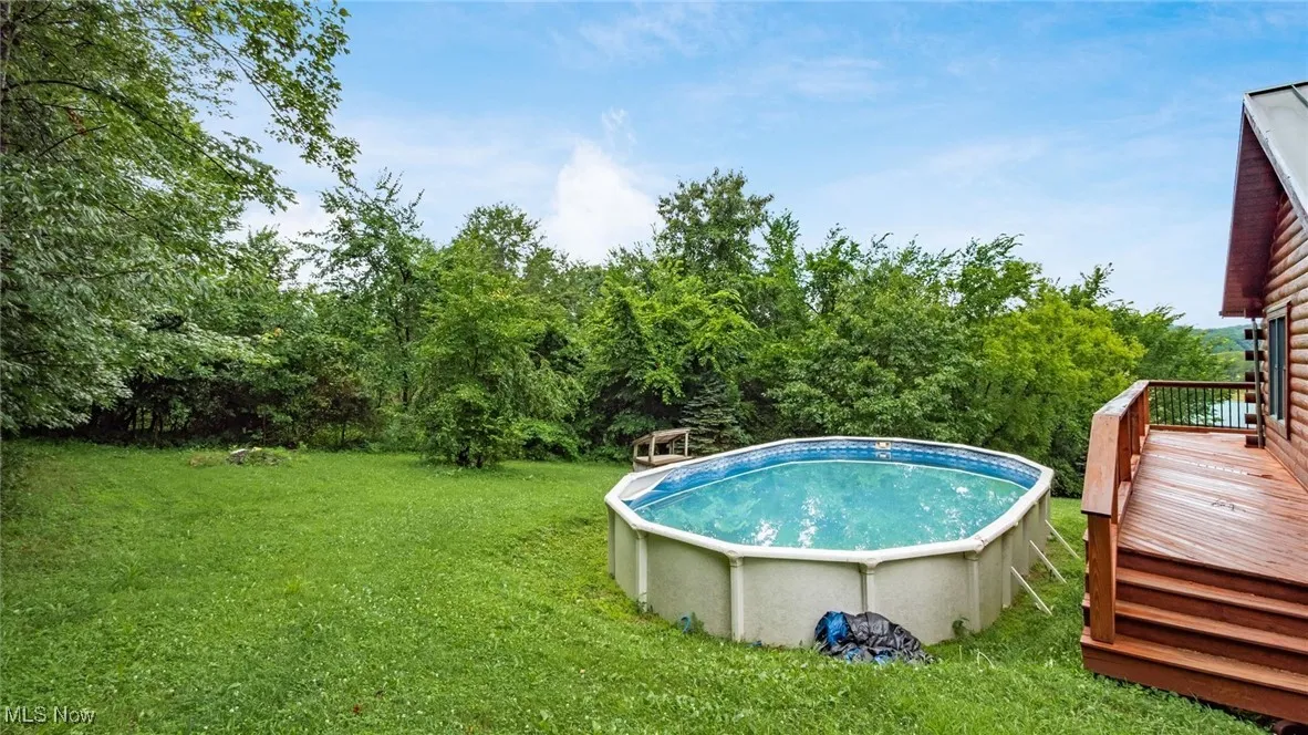 Outdoor pool featuring a deck and a yard