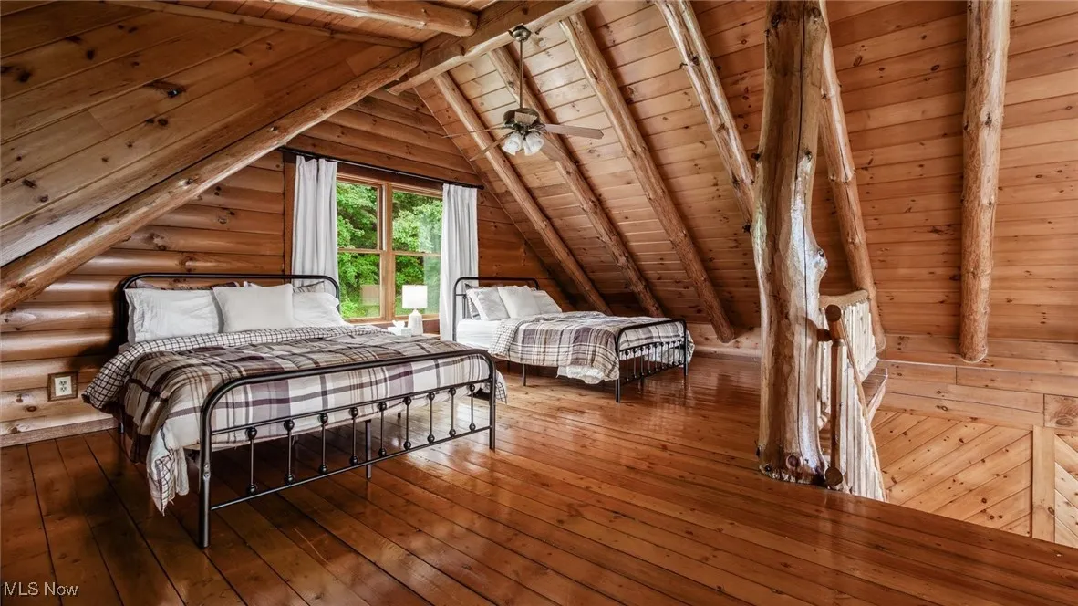 Bedroom with wooden ceiling, wood-type flooring, and log walls