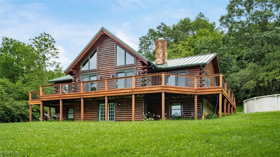 Rear view of house with a wooden deck, a yard, and a metal roof