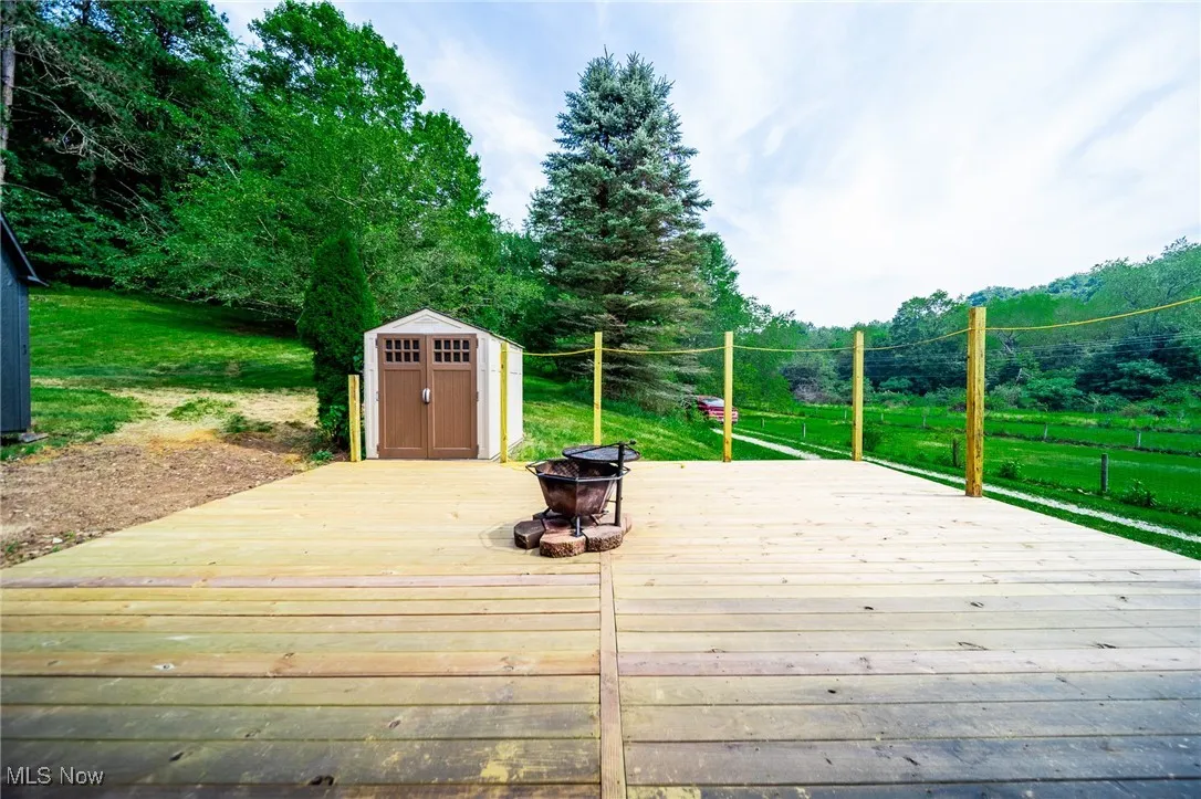 Deck featuring a fire pit, a storage unit, and a yard