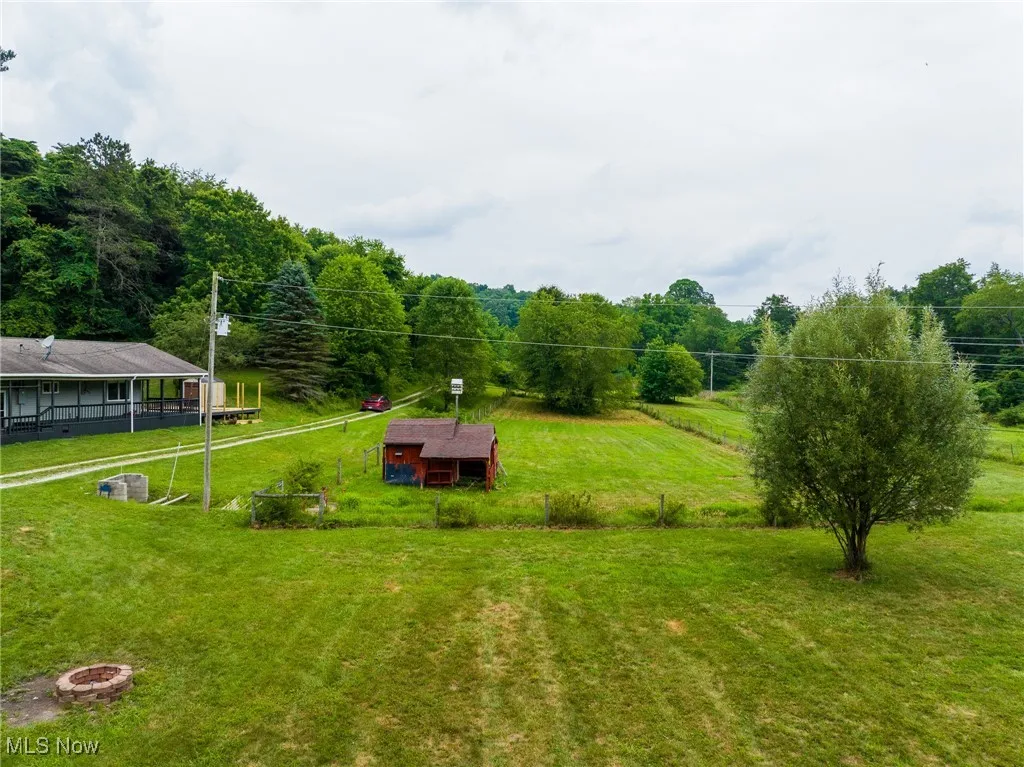 View of grassy yard with an outbuilding and a view of trees