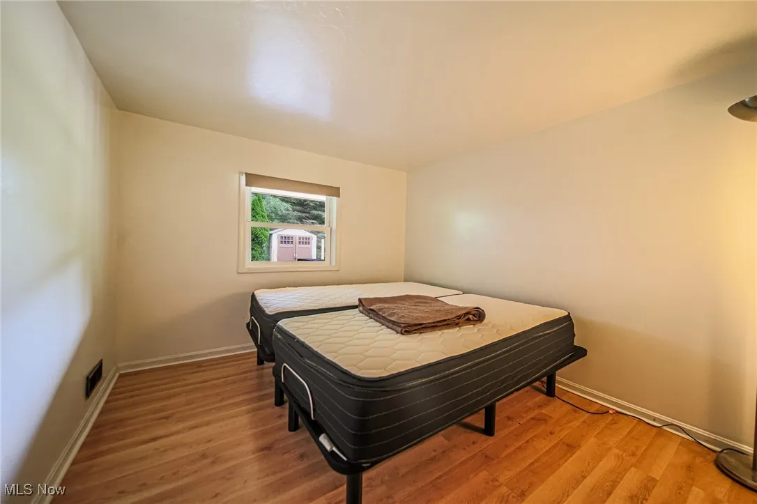 Living area with vaulted ceiling, a glass covered fireplace, ceiling fan, and wood finished floors