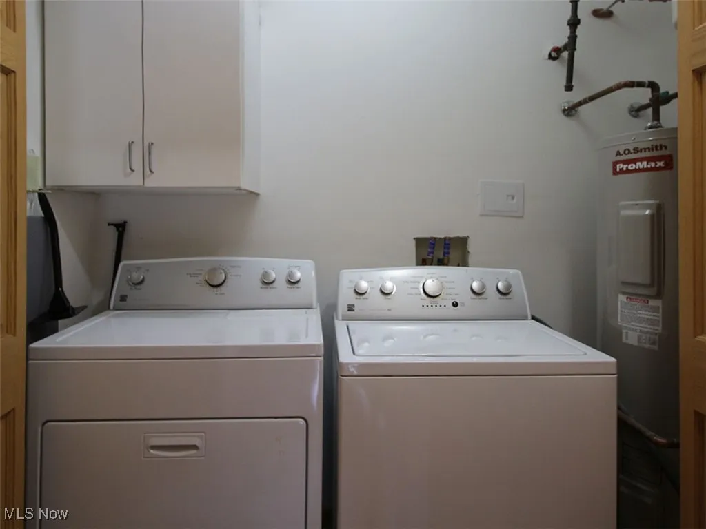 Laundry room with washer and dryer, electric water heater, and cabinet space