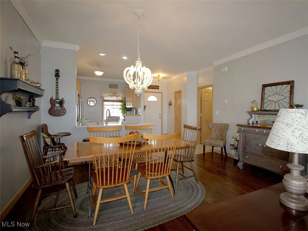 Dining area with a chandelier, wood finished floors, and crown molding