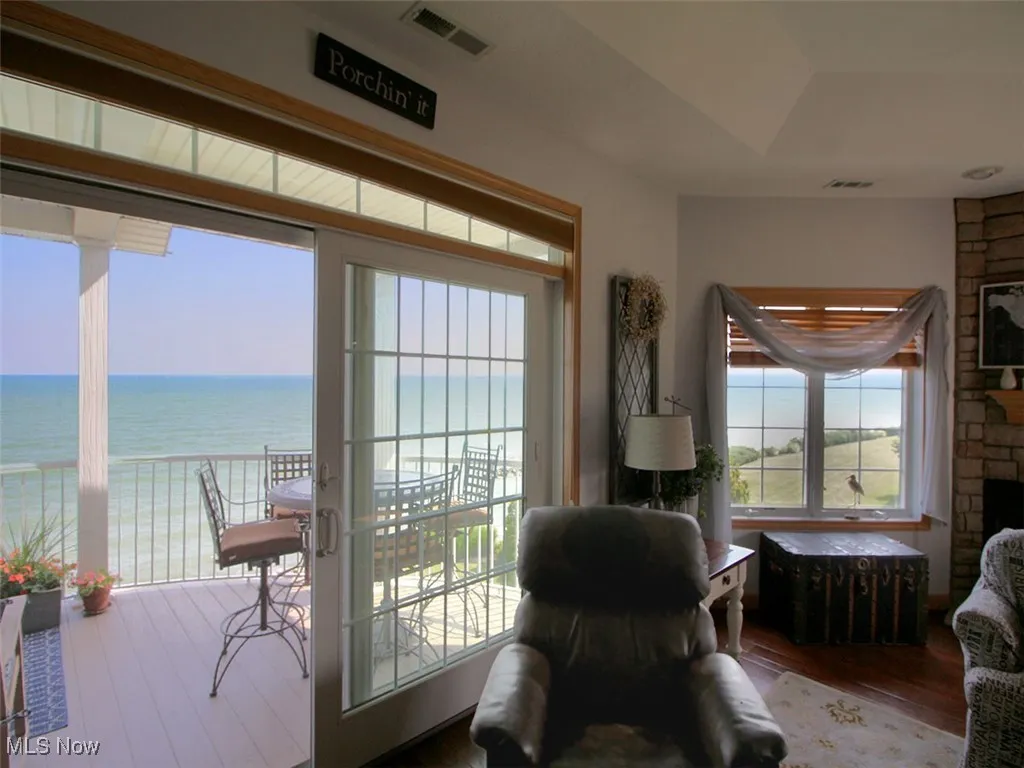 Living area featuring wood finished floors, a stone fireplace, and a water view
