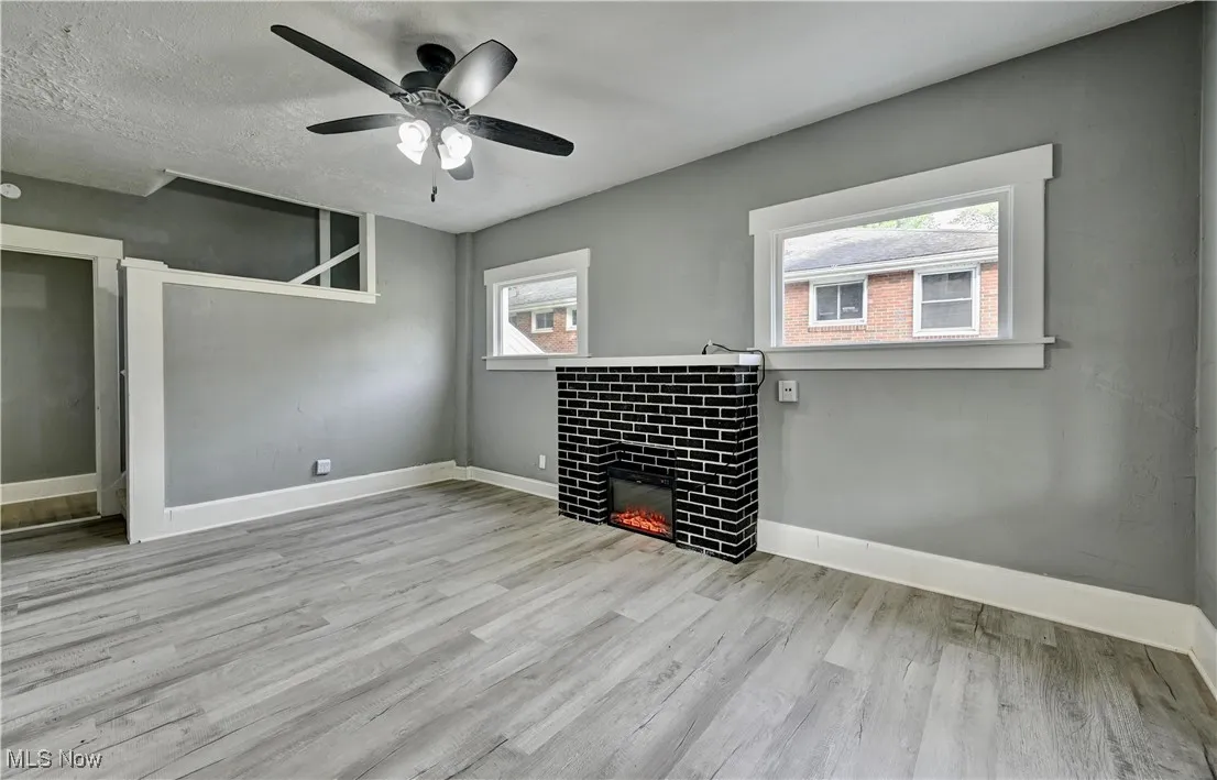 Unfurnished living room with wood finished floors, a tile fireplace, and ceiling fan