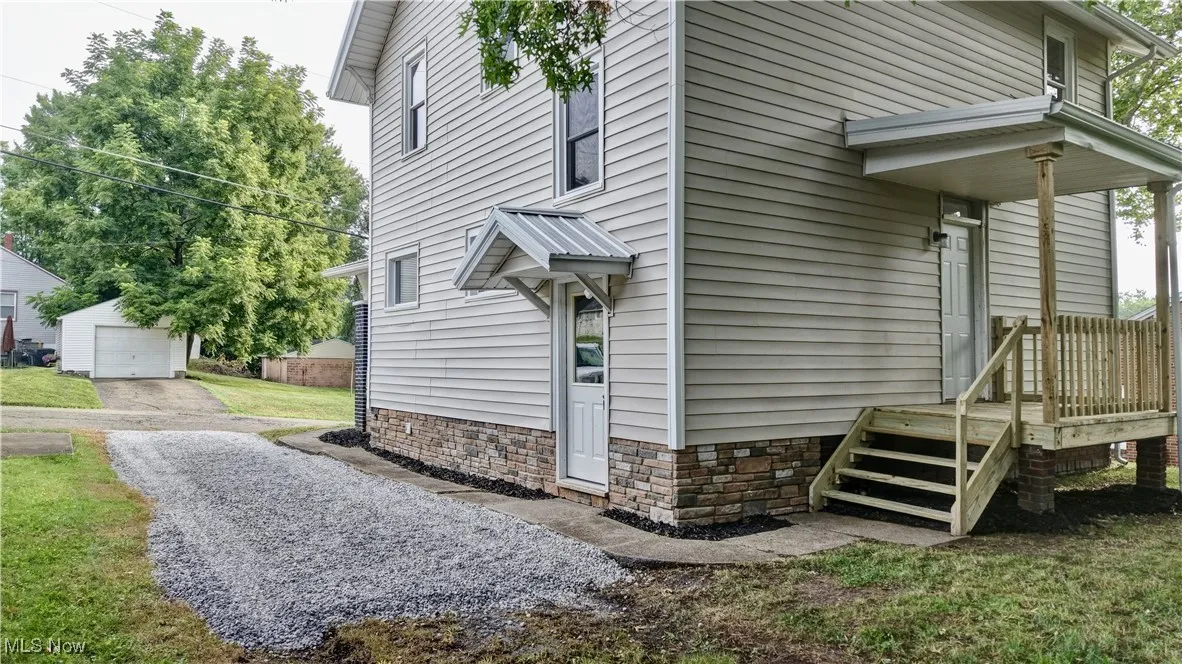 View of property exterior featuring a garage, driveway, an outdoor structure, and a lawn
