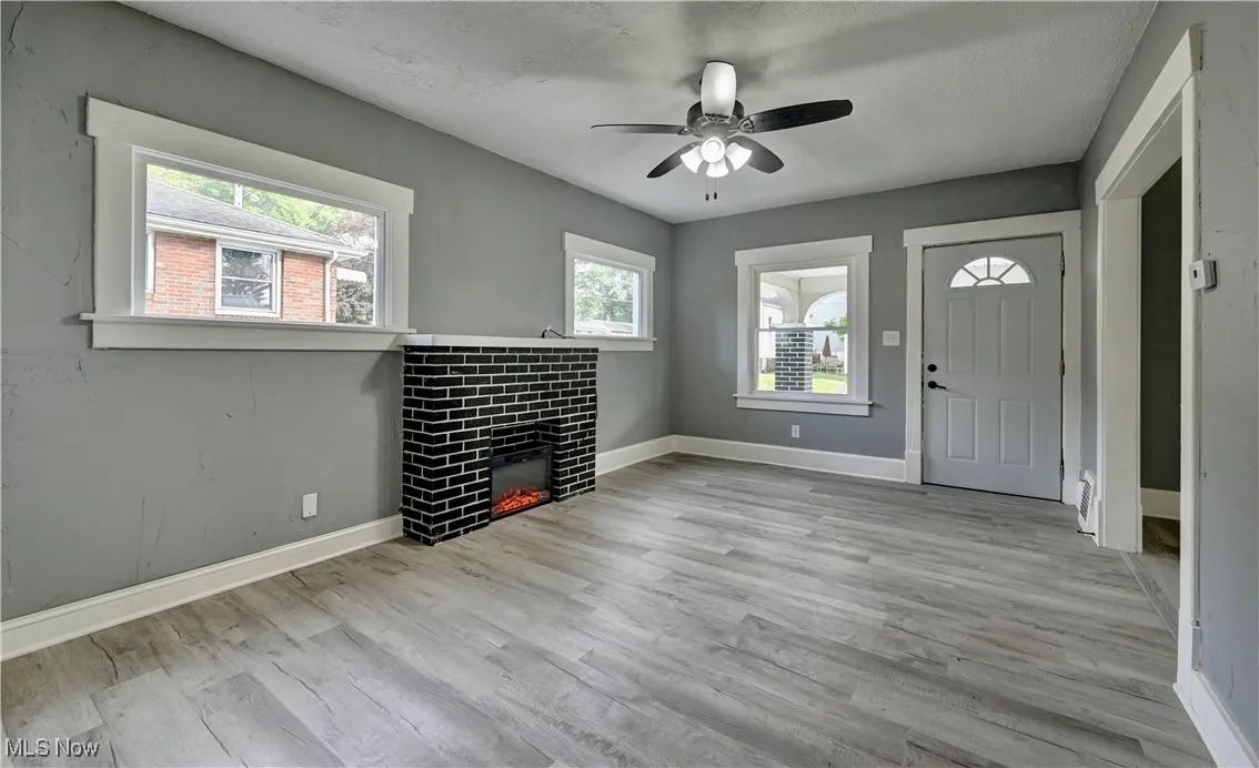 Unfurnished living room with a ceiling fan, a tile fireplace, and wood finished floors