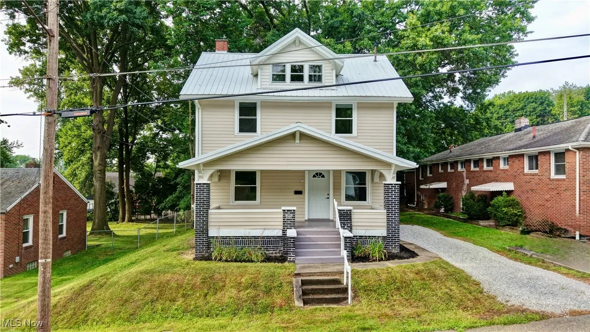Traditional style home featuring covered porch, a metal roof, driveway, and a chimney