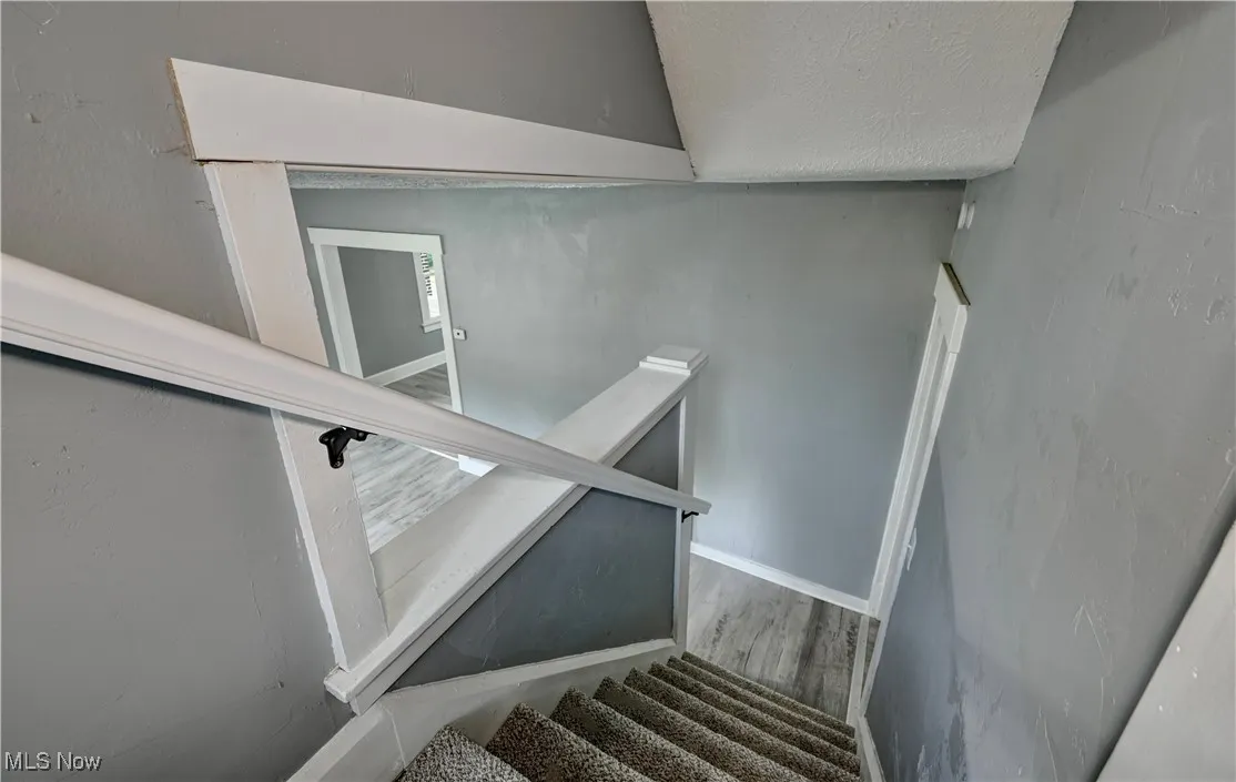 Stairway with wood finished floors and a textured ceiling