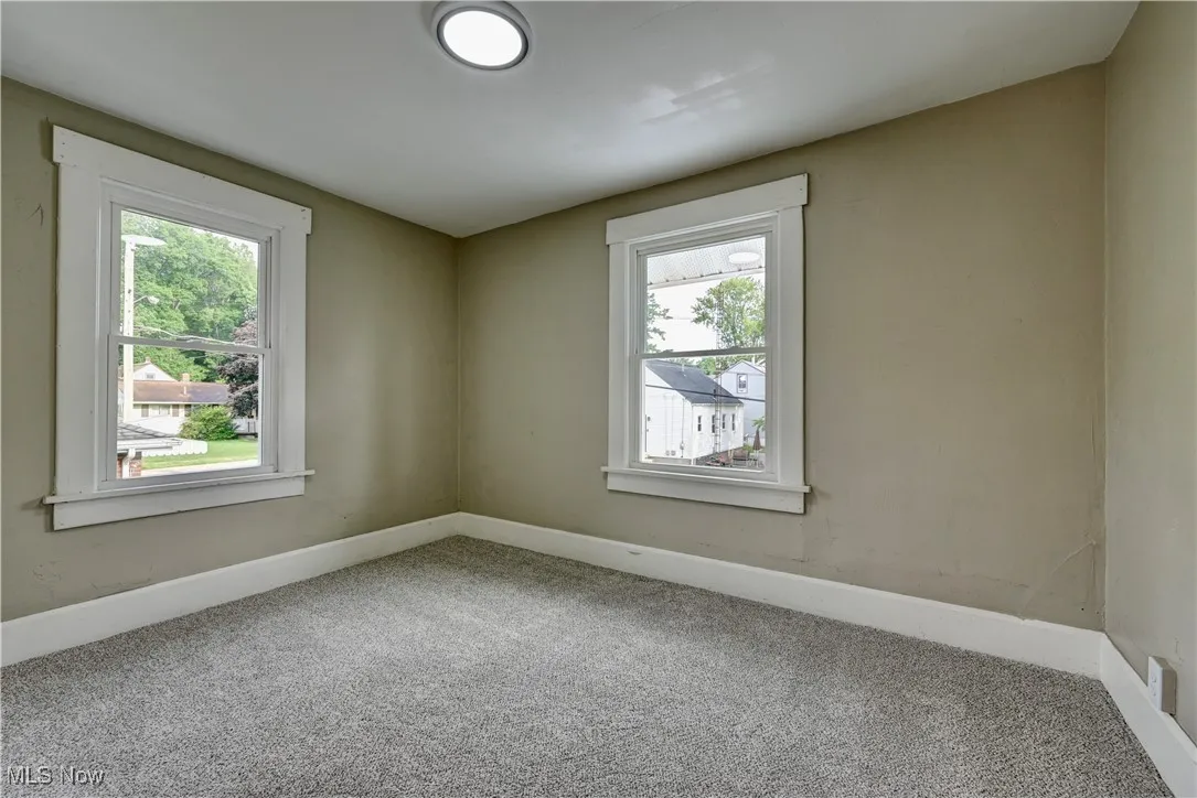 Carpeted spare room featuring baseboards