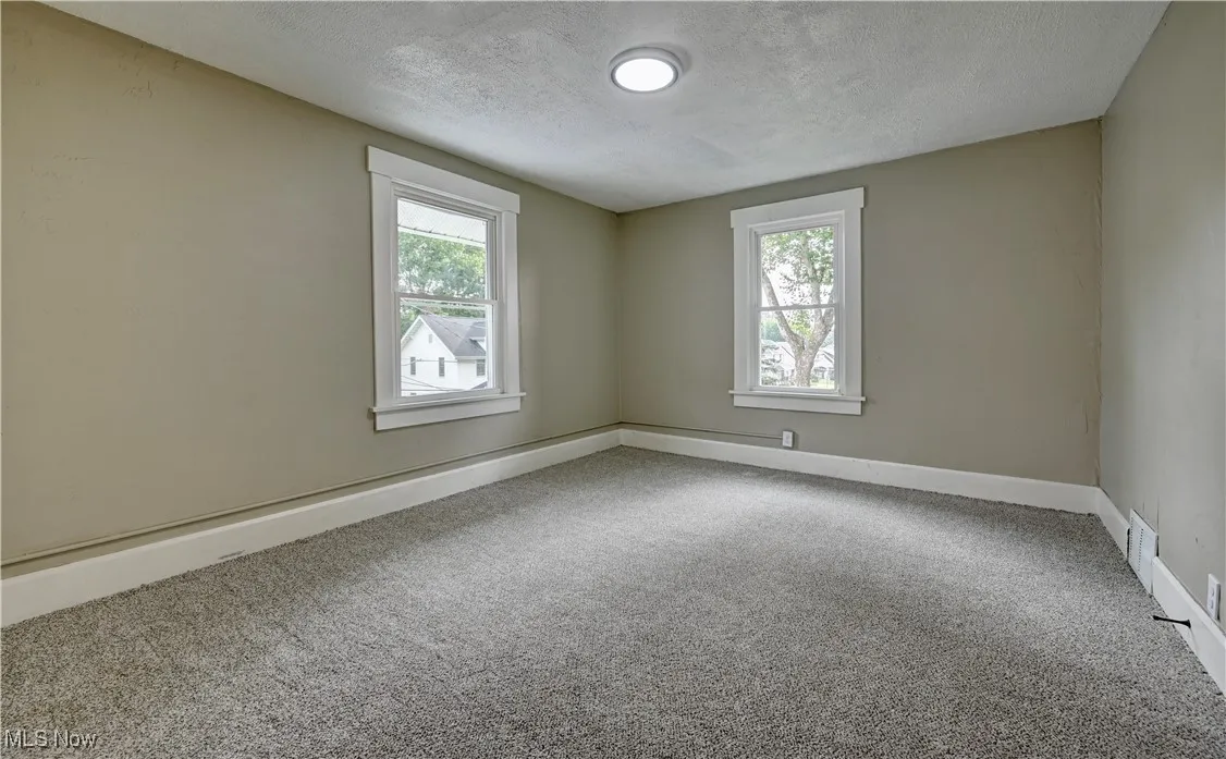 Carpeted spare room with plenty of natural light and a textured ceiling