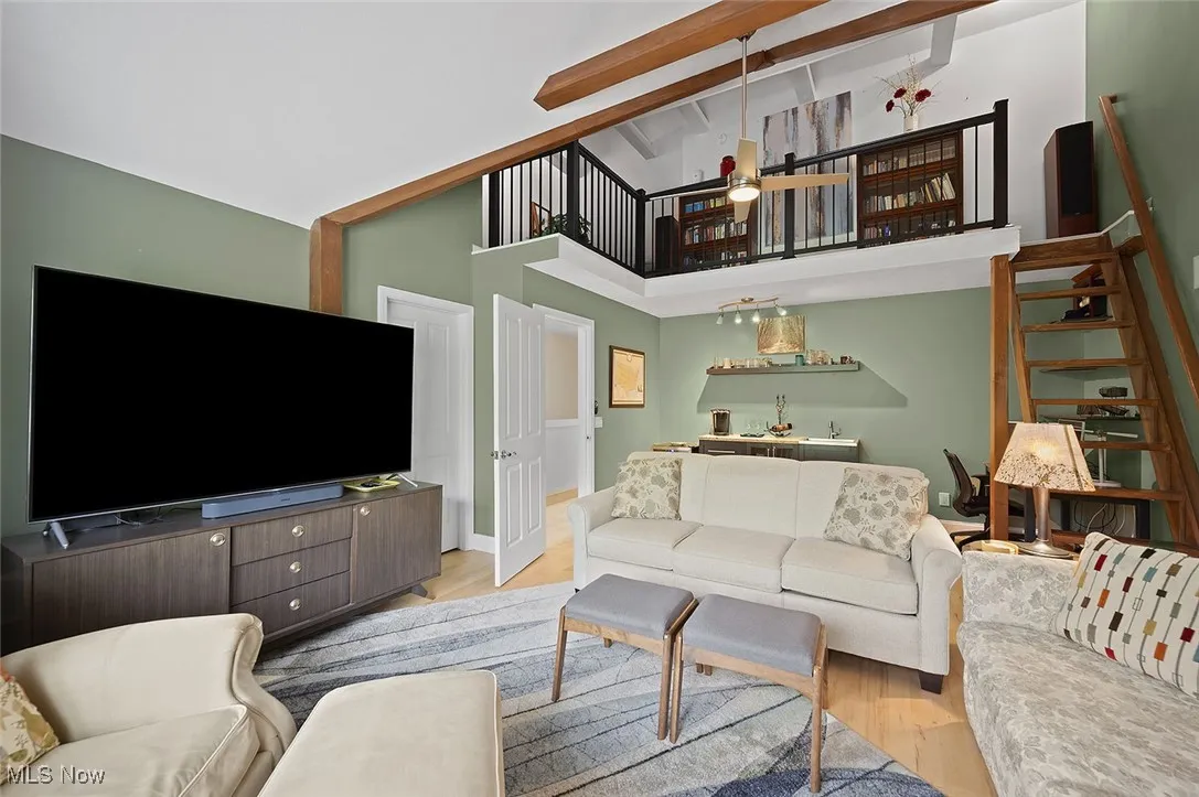 Living area featuring bar with sink, light wood-style flooring, and high vaulted​​‌​​​​‌​​‌‌​‌‌​​​‌‌​‌​‌​‌​​​‌​​ ceiling