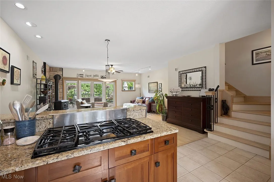 Kitchen featuring black gas cooktop, open floor plan, brown cabinets, light tile patterned flooring, and recessed lighting
