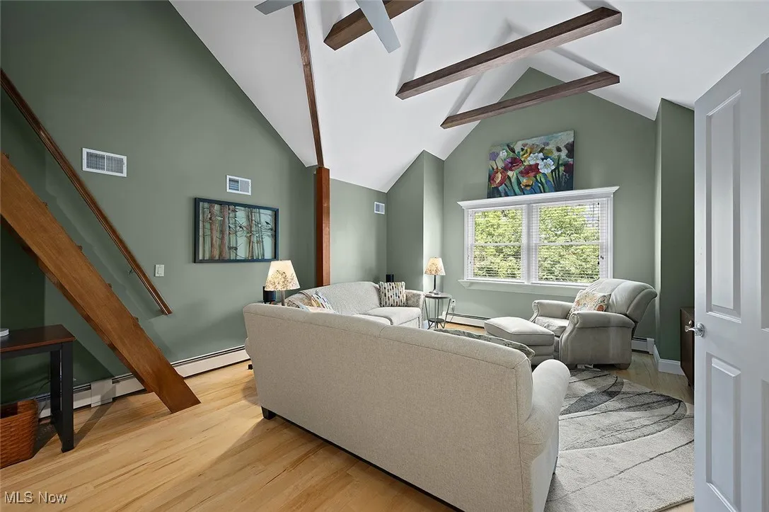 Living room with stairway, light wood-style flooring, and baseboard heating
