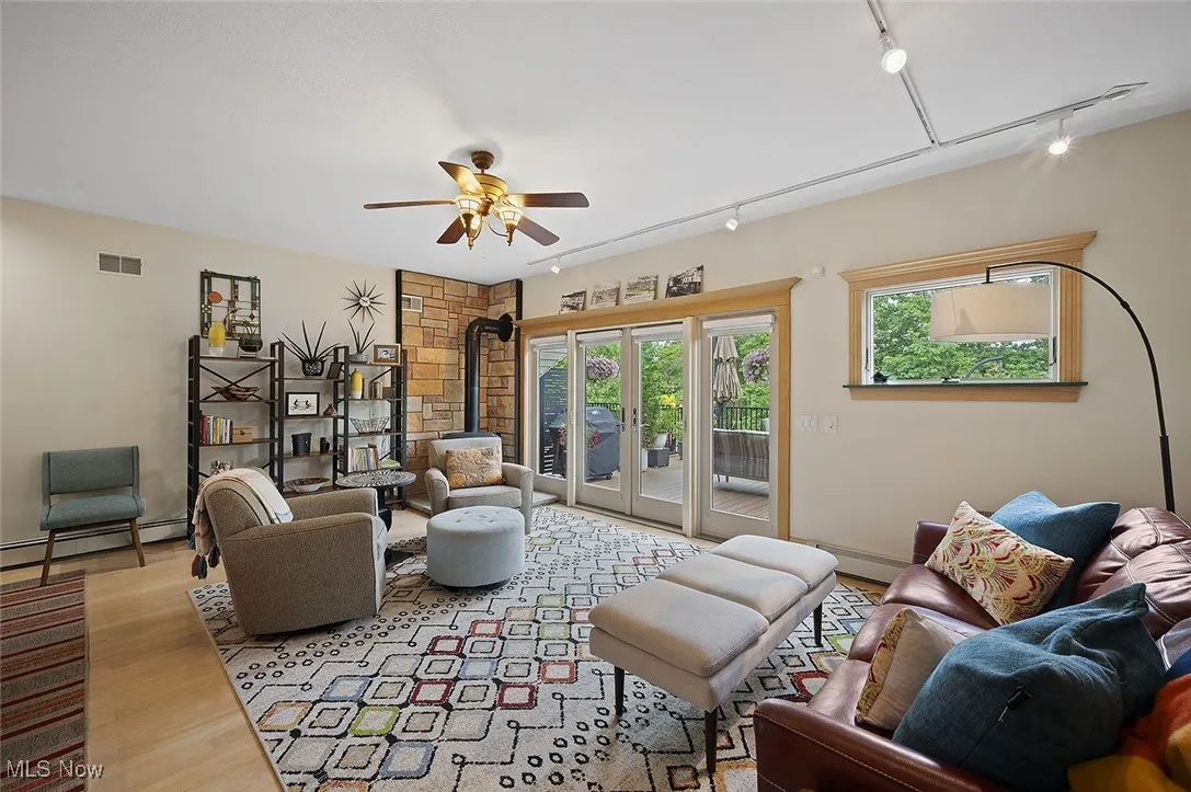 Living room featuring track lighting, a wood stove, wood finished floors, and ceiling fan