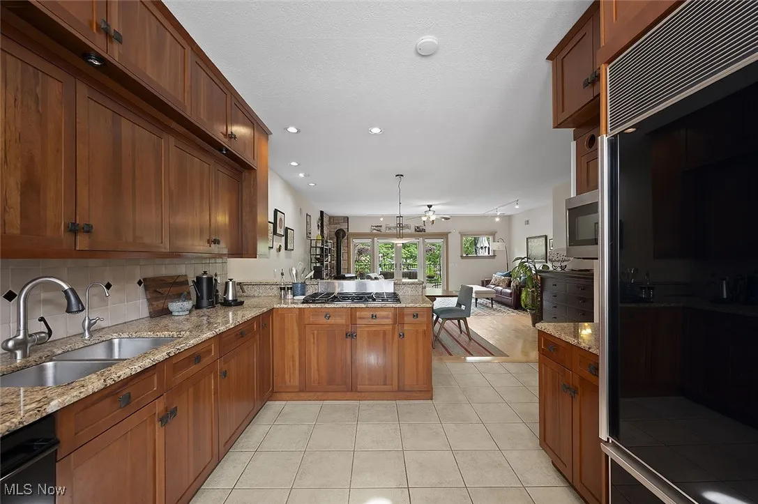 Kitchen featuring fridge, open floor plan, a peninsula, decorative backsplash, and light tile patterned floors
