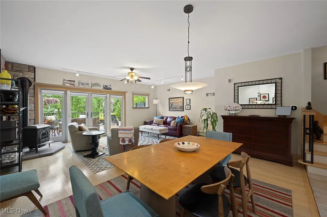 Dining space featuring a wood stove, light wood-style flooring, and ceiling fan