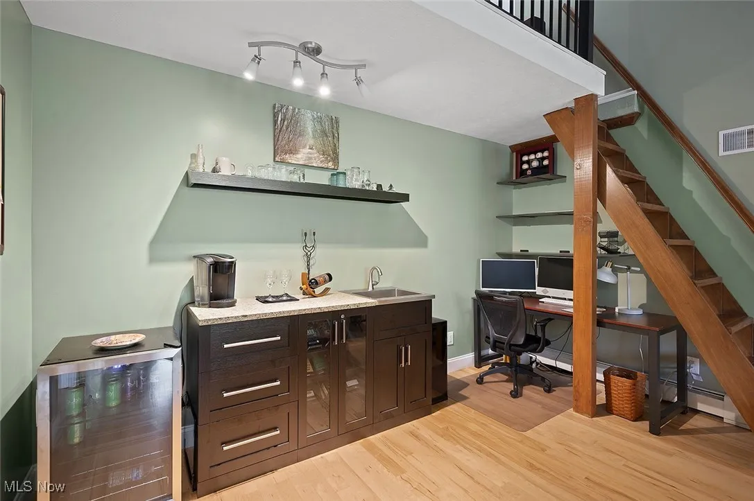 Indoor wet bar featuring light wood-style flooring and stairway