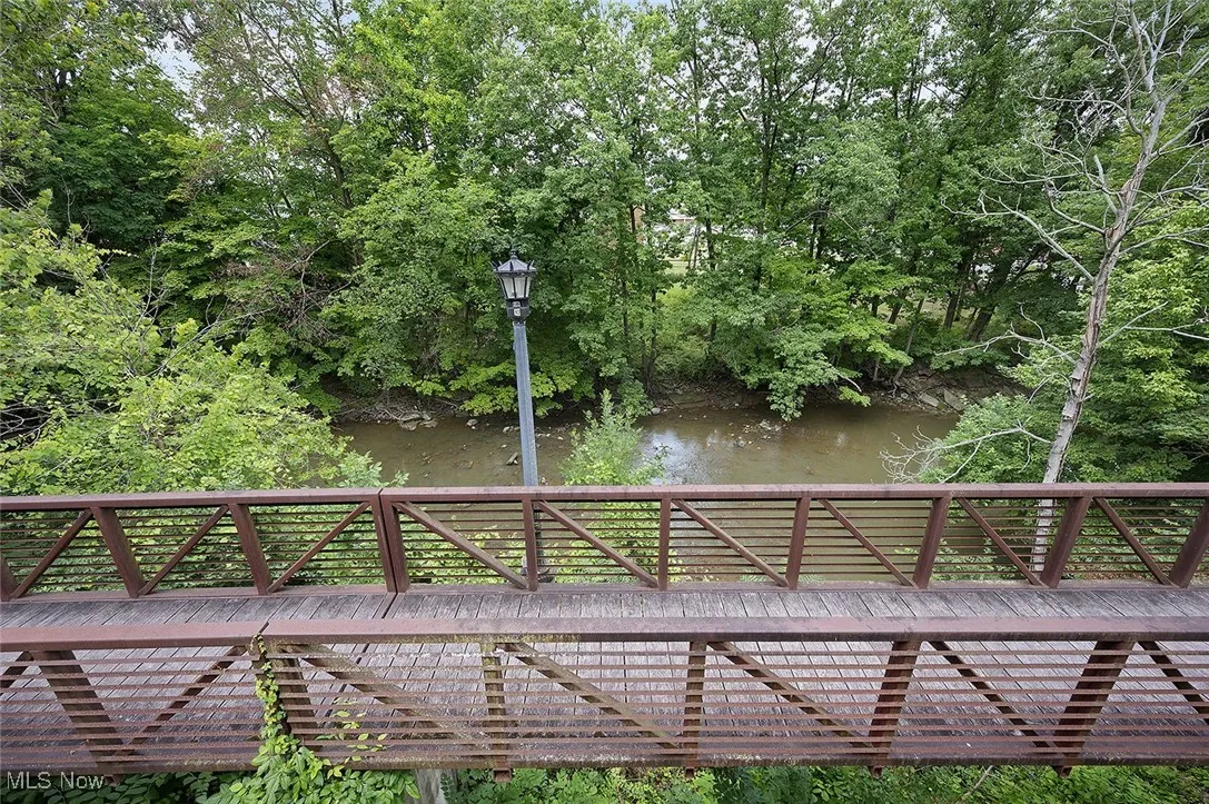 View of property's community featuring a deck with water view and view of scattered trees