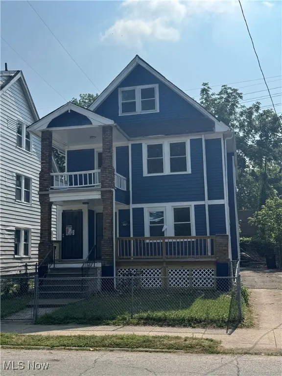 View of front facade with a balcony, a fenced front yard, a gate, and covered porch