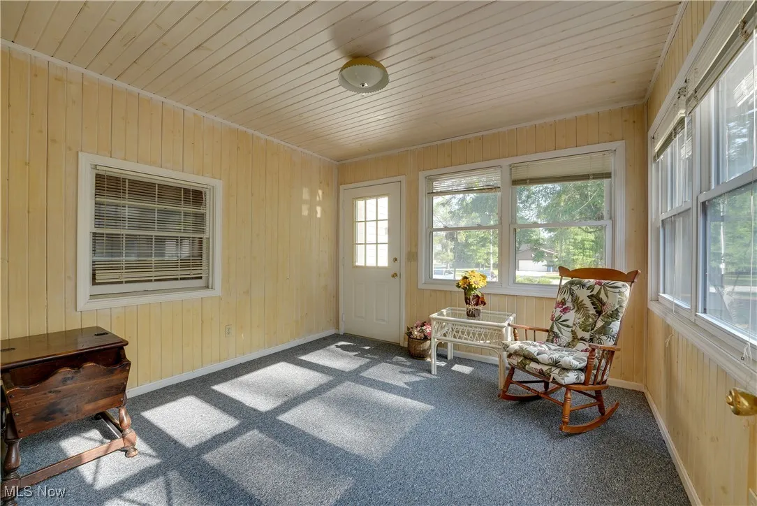 Sunroom with carpet flooring, wooden walls, and wood ceiling