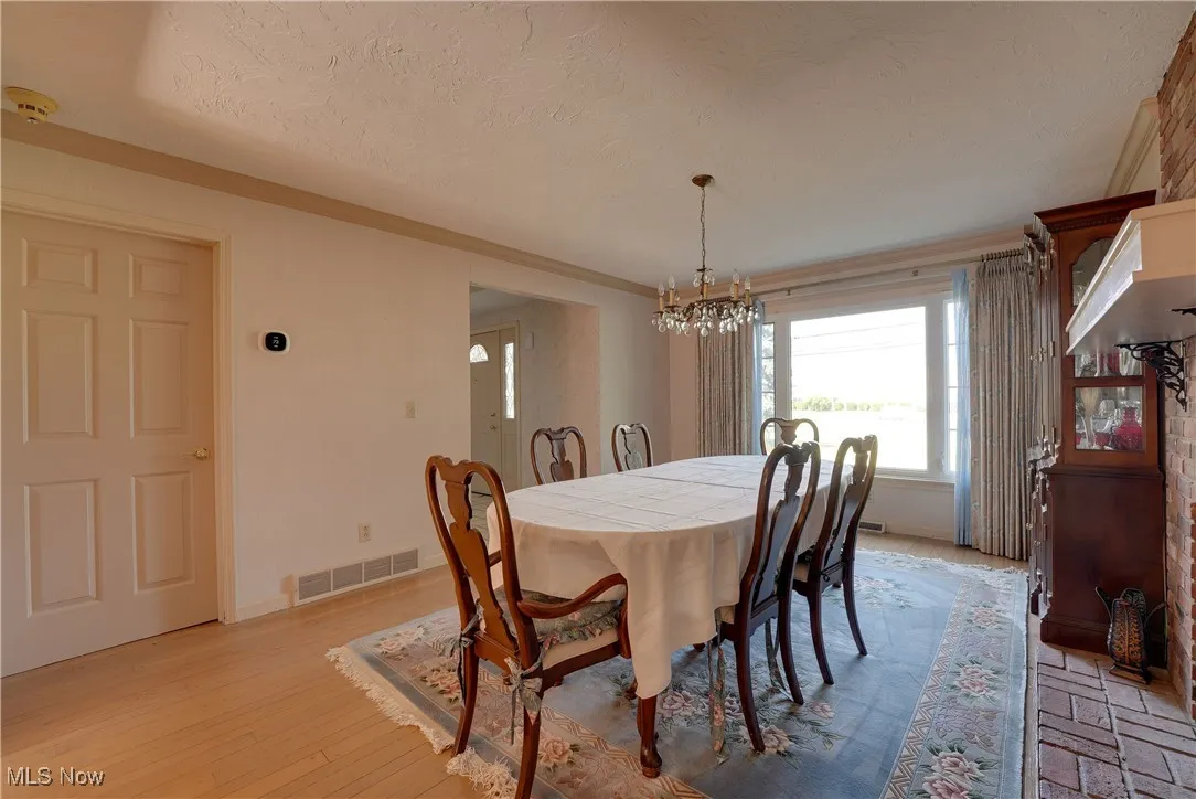Dining area with a chandelier, a textured ceiling, and light wood-style flooring