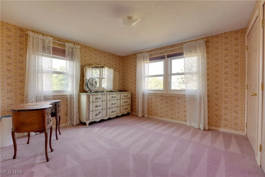 Bedroom featuring wallpapered walls and light colored carpet