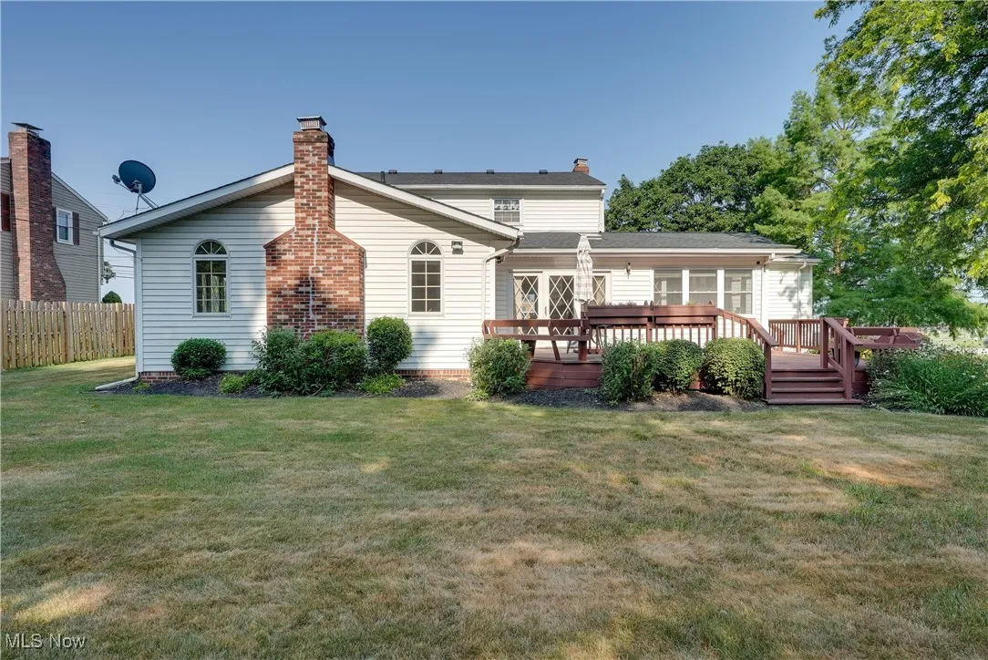 Rear view of property featuring a chimney and a wooden deck