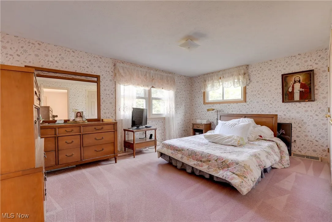 Bedroom featuring wallpapered walls and light colored carpet