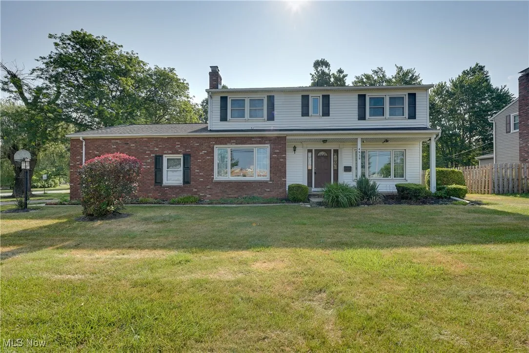 Traditional home featuring a chimney, brick siding, and covered porch