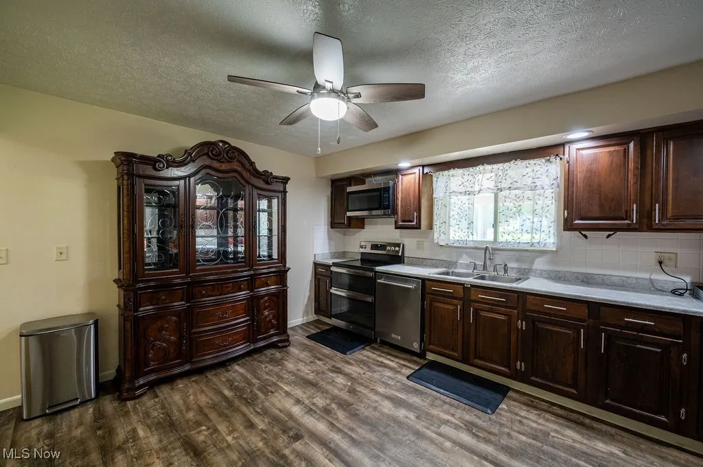 Kitchen featuring ceiling fan, light countertops, dark wood finished floors, stainless steel appliances, and backsplash