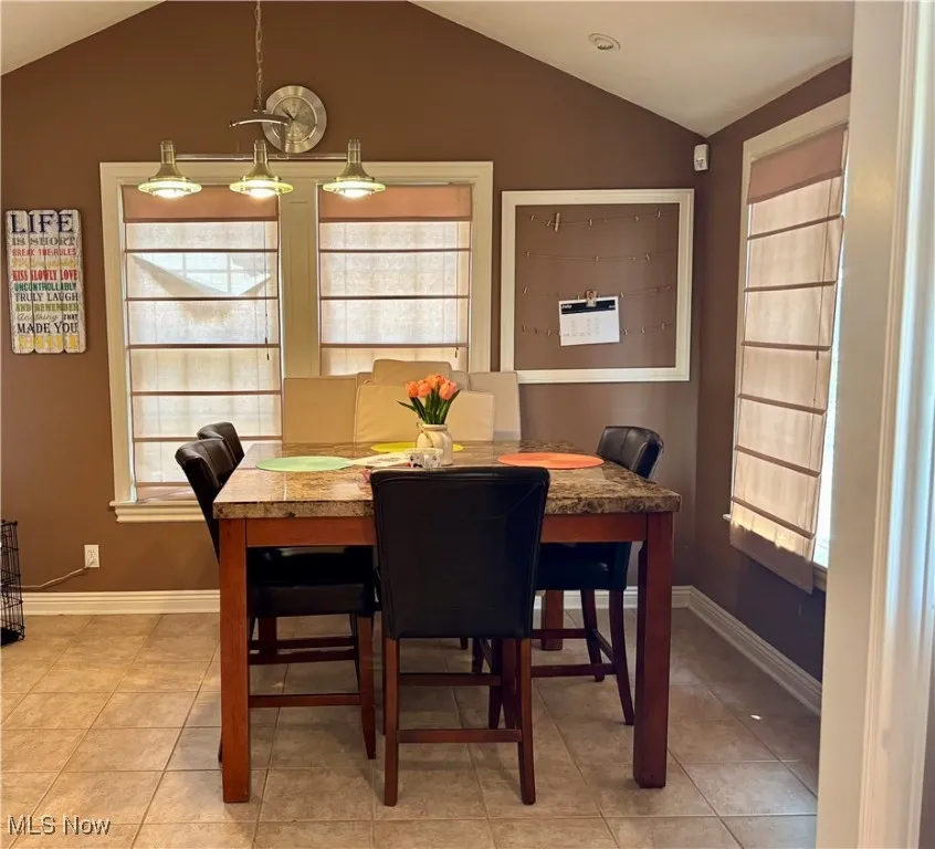 Dining area with vaulted ceiling and light tile patterned flooring